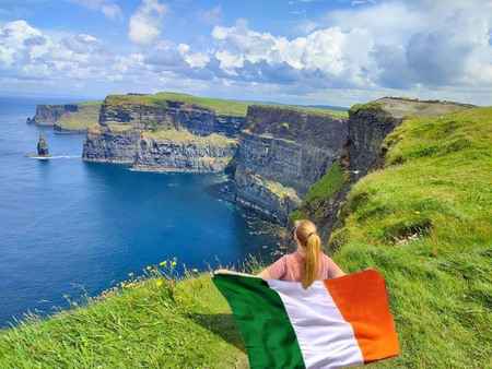 Tourists admiring the stunning ocean views from the Cliffs of Moher, Ireland’s most famous coastal cliffs.