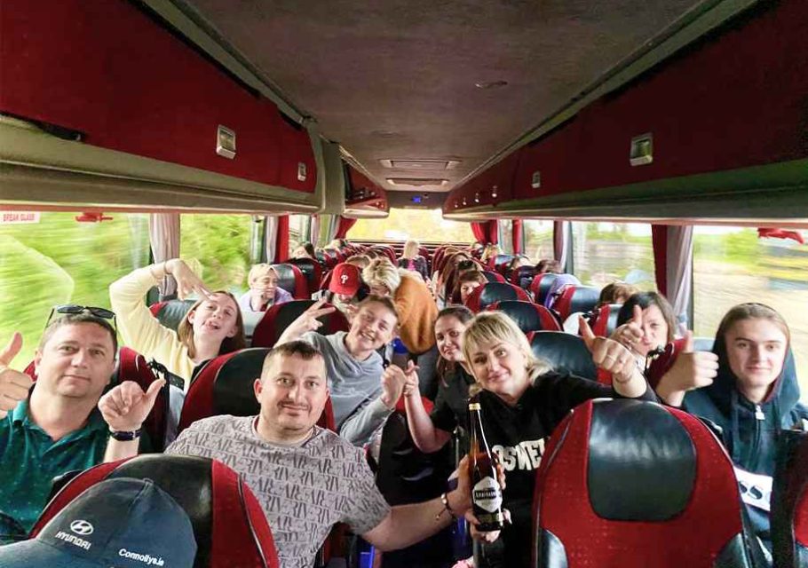 Happy group of travelers in a private tour bus enjoying a custom Irish tour through scenic Ireland.