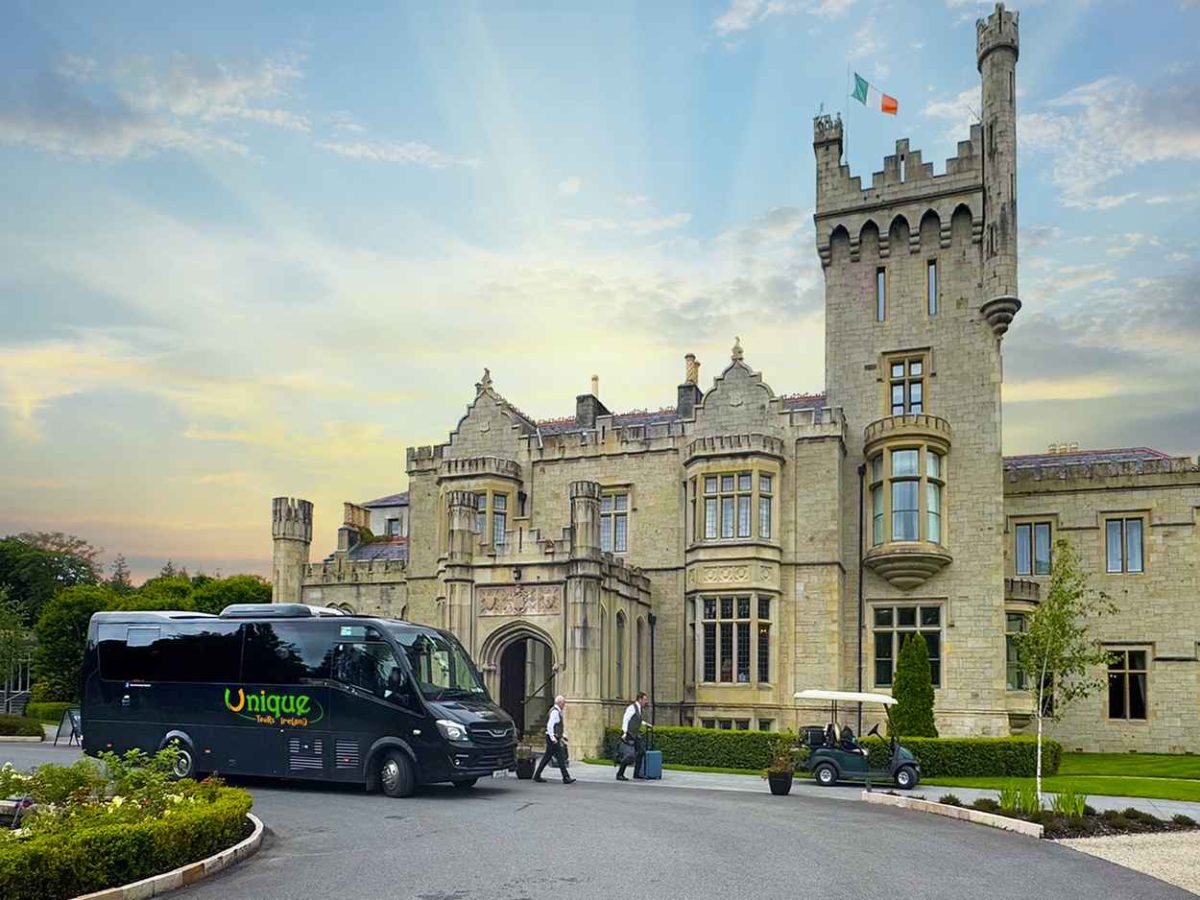 Luxury small group tour in Ireland near Donegal with branded coach beside a historic castle hotel